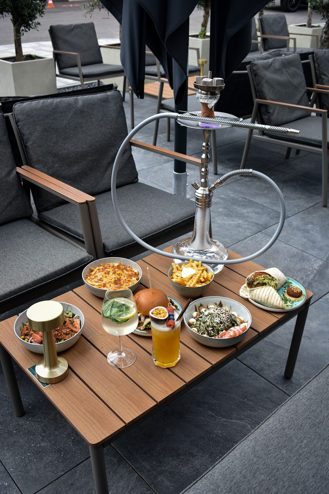Mezze-Schalen, Shisha und Getränke auf dem Terrassentisch